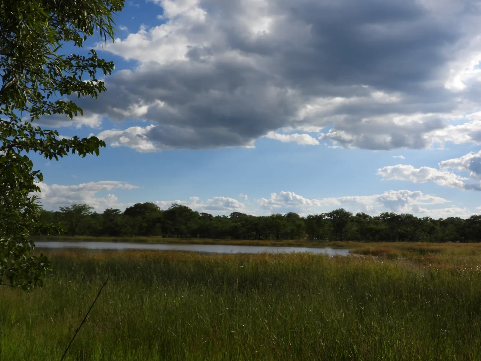 Clouds over open ground and a dam at Khami