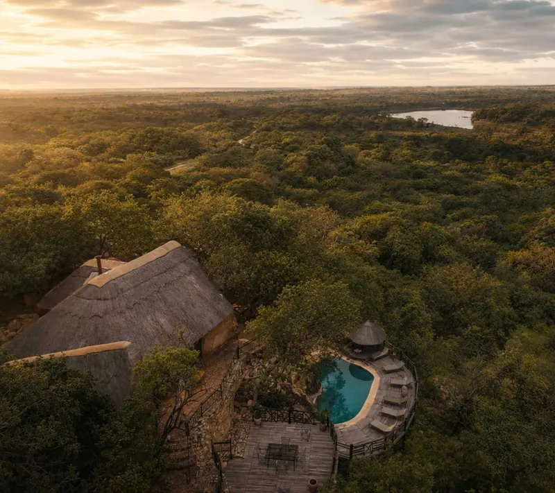 Khami Lodge and its pool from above, set among granite and trees